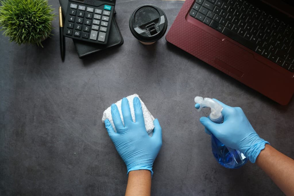 UrbanMove Removals Man and Van Cleaning Services Ltd cleaner sanitising a desk and workspace during office cleaning in Aberdeen